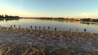 Line of Surfers Surfing Tidal Wave Aftermath on Saint Pardon