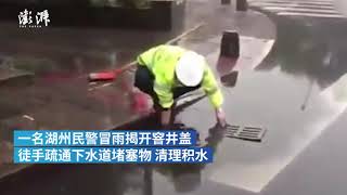 执勤交警在大雨中，徒手疏通下水道。被网友称为“最美背影”。