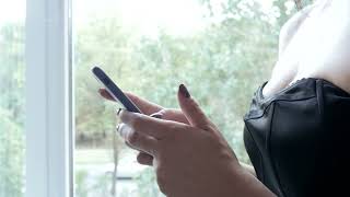 young brunette woman use mobile smart phone by the window