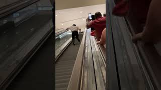 Man runs up down escalator as group cheers him on