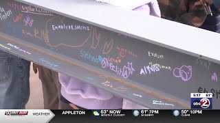 Elementary students in Oshkosh sign construction beam as renovations begin
