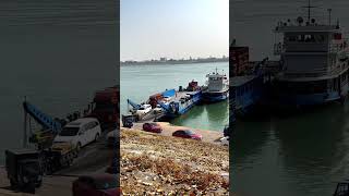 Five big trucks are crossing the river by boat. The ferry is crossing the river. Beautiful scenery