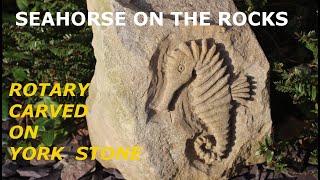 STONE CARVING A SEAHORSE ON A BOULDER.