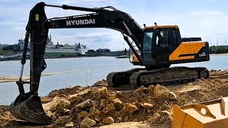 The excavator scatters stones on the embankment of the river