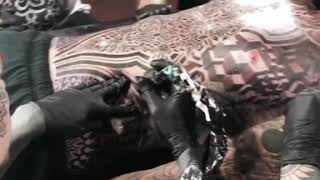 Five tattoo artists tattooing one man at the same time