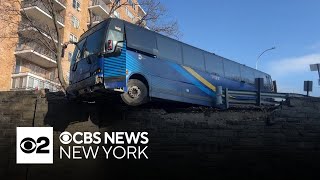 MTA bus crashes through retaining wall, dangles over roadway