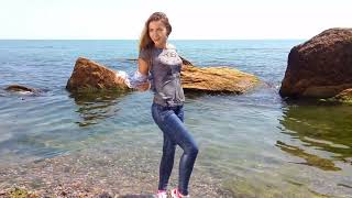 a girl in jeans and a shirt gets wet in the water