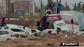 People climb onto vehicles tossed around by powerful floodwaters in Iran