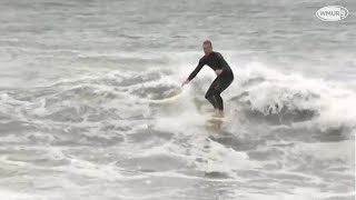 Surfer rides waves during high tide at Hampton Beach