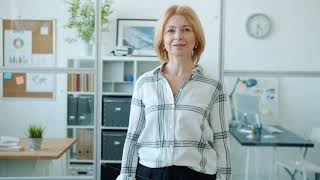 Slow motion portrait of attractive mature businesswoman smiling standing in office room