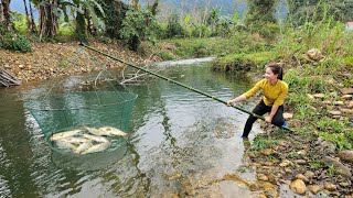 Traditional fishing method. Ana uses a green net to fish in a large stream.