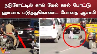 நடுரோட்டில் கால் மேல் கால் போட்டு ஹாயாக படுத்துகொண்ட போதை ஆசாமி