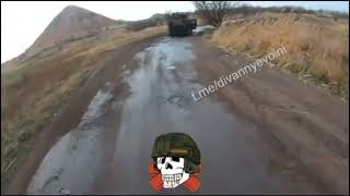 Russian soldier on a bicycle rides by burned Ukrainian Kozak MRAP