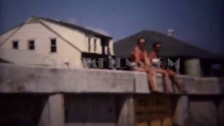 1949: Women sitting on pier overlooking sunny ocean beach waves.  HOLLYWOOD, FLORIDA