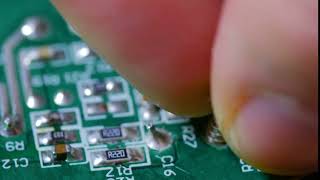 close up macro shot of hand twisting out screw on an electronic chip circui