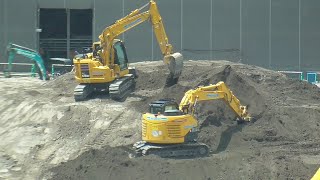 A hydraulic excavator digs dirt at a construction site.