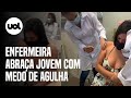 Enfermeira abraça jovem com medo de agulha durante vacinação contra covid