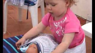 Funny little girl puts her baby doll to bed