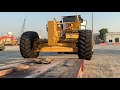 caterpillar 24h motor grader transporting and unload over size machine heavy equipment mega machine.