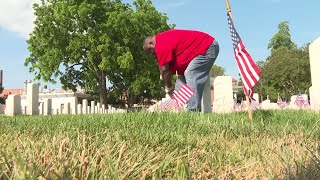 Volunteers place flags at graves in Hampton National Cemetery ahead of Memorial Day