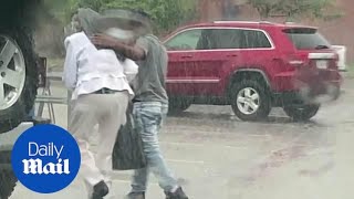 Teen helps elderly woman cross a parking lot and shield her from rain