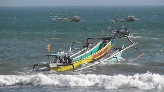 Fishermen confronted by waves at Puger Beach