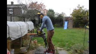 Manly cutting a log with a Titan Electric chainsaw