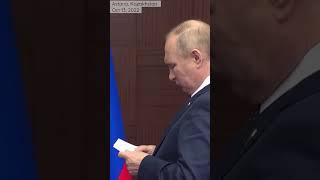 What is Putin reading when waiting for shaking hands with Turkey’s Erdogan