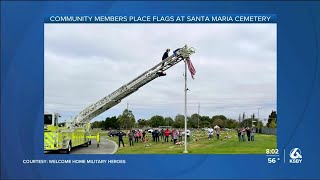Community members place flags at Santa Maria Cemetery in honor of those lost