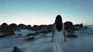 mixkit woman walking on beach towards boulders download free videos for YouTube