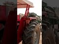 Tractor with threshing machine harvesting wheat crop in village