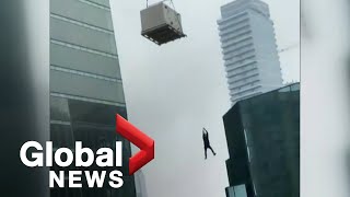 Construction worker seen dangling from crane in Toronto
