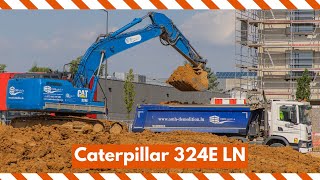 Big blue Caterpillar 324E loading dump trucks with dirt