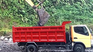 excavator works to dredge sandstone then load it into a dump truck - 4k