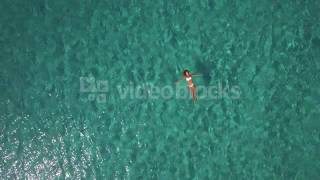 aerial beautiful young woman floating on water surface in crystal clear ocean njdvj0grg