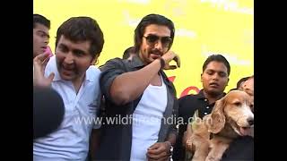 John Abraham in tight white T-shirt, at a Police Dog event, shares stage with pooches of all ilk