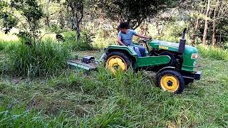 Tractor chapeando el pasto grande y maleza.