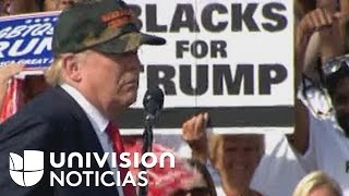 Una mujer blanca sostiene una pancarta de 'Blacks for Trump' en un evento en Florida