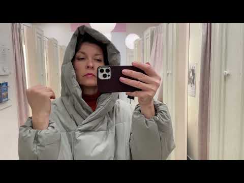 примерка пуховика перед зеркалом в магазине