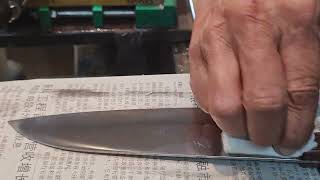 Polishing a Hiromoto Honyaki Santoku knife using a handheld buffing wheel