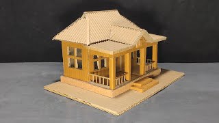 Simple Miniature Cardboard House with porch and cross gable roof.