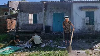 Two young men help an old woman clear weeds on the island.