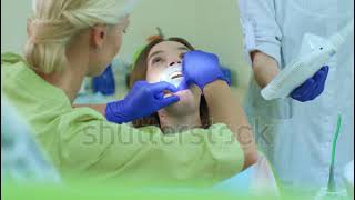 female dentists in purple latex gloves put cheek retractor in female patient's mouth