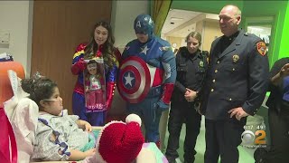 Police And Superheroes Bring Hospitalized Children Holiday Cheer