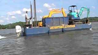 Amphibious Excavator being towed home passes a coal barge