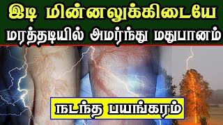 இடி மின்னலுக்கிடையே மரத்தடியில் அமர்ந்து மதுபானம் அருந்திய நபர்கள்