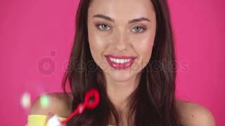 Studio shoot of happy young woman blowing soap bubbles isolated on crimson