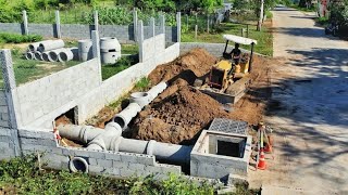 Clearing land to bury the drainage system next to the house fence and concrete road.