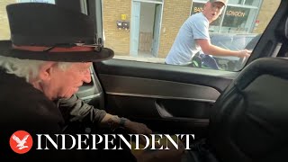 Keith Richards jokes with cyclists as he signs autograph for him in back of taxi