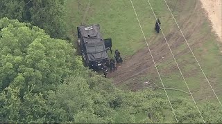 Wanted murder suspect barricaded inside home after firing at officers, police say